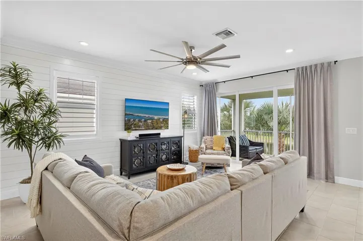 Living area featuring light tile patterned floors, ceiling fan, ornamental molding, recessed lighting, and wood walls