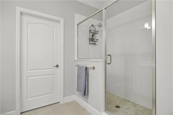 Bathroom with a stall shower, light tile patterned floors, and ornamental molding
