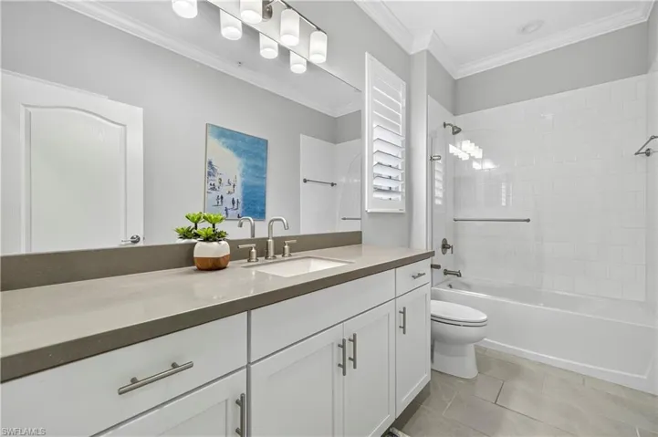 Bathroom featuring shower / tub combination, vanity, light tile patterned floors, and ornamental molding