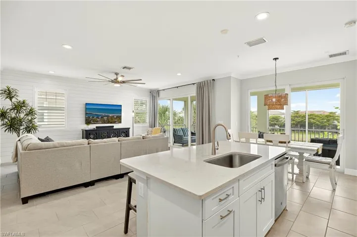 Kitchen with white cabinets, healthy amount of natural light, light stone countertops, crown molding, and recessed lighting