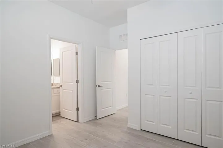 Unfurnished bedroom with ensuite bath and a closet