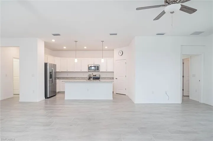 Kitchen featuring pendant lighting, a kitchen island with sink, white cabinets, ceiling fan, and stainless steel appliances