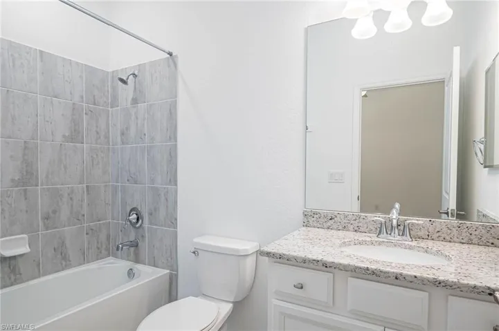 Full bathroom featuring vanity, tiled shower / bath combo, and toilet