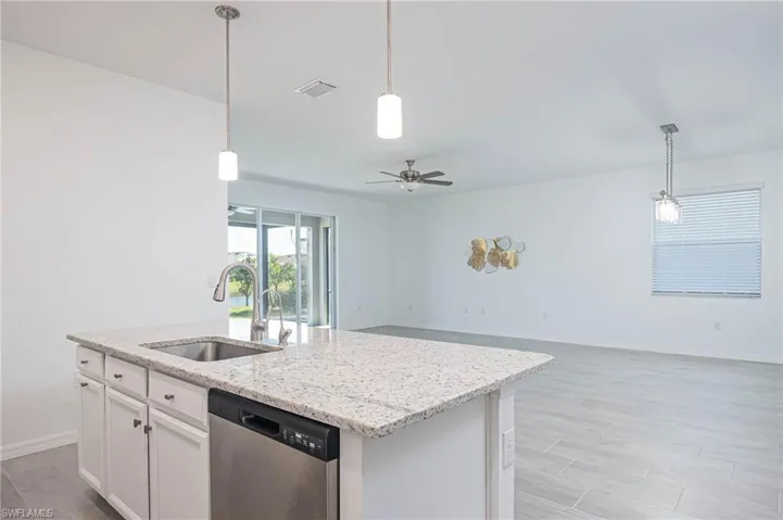 Kitchen featuring white cabinetry, dishwasher, ceiling fan, sink, and a center island with sink