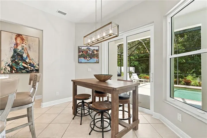 Rectangular dining table with stools, expansive sliding glass doors, large window, tile flooring, and a linear chandelier