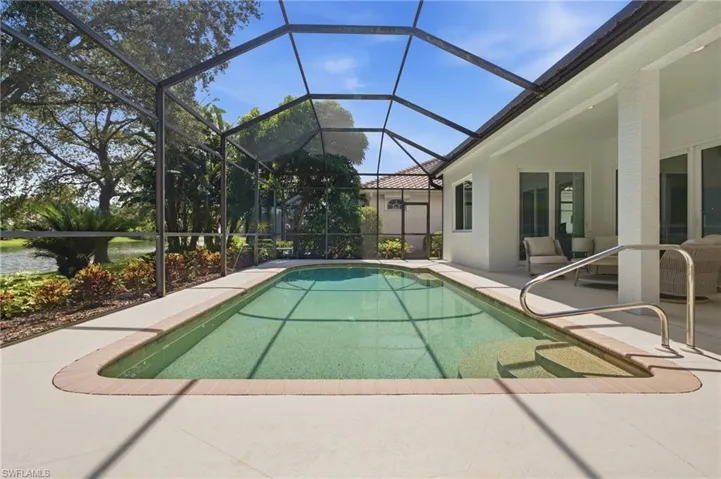 Screen-enclosed swimming pool with integrated steps, surrounded by a spacious paved patio and covered lanai