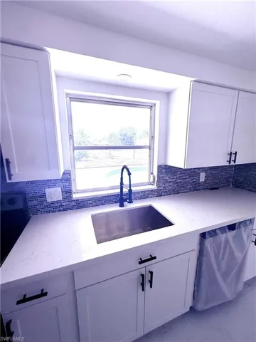 Kitchen with dishwasher, light stone countertops, decorative backsplash, and a sink