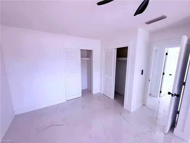 Unfurnished bedroom with visible vents, marble finish floor, baseboards, and a ceiling fan