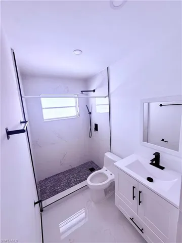 Full bath with marble finish floor, vanity, a marble finish shower, and toilet