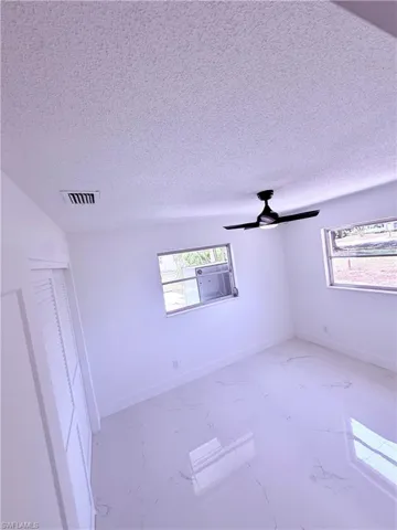 Empty room featuring marble finish floor, a healthy amount of sunlight, and visible vents