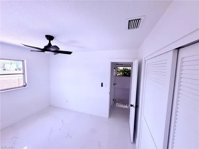Unfurnished bedroom featuring a ceiling fan, visible vents, a textured ceiling, and a closet