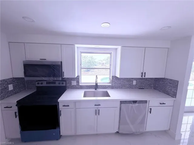 Kitchen with light countertops, a sink, white cabinetry, and appliances with stainless steel finishes