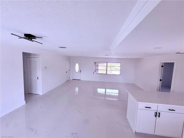 Empty room featuring a textured ceiling, marble finish floor, and baseboards