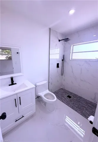Bathroom featuring a marble finish shower, vanity, marble finish floor, toilet, and recessed lighting