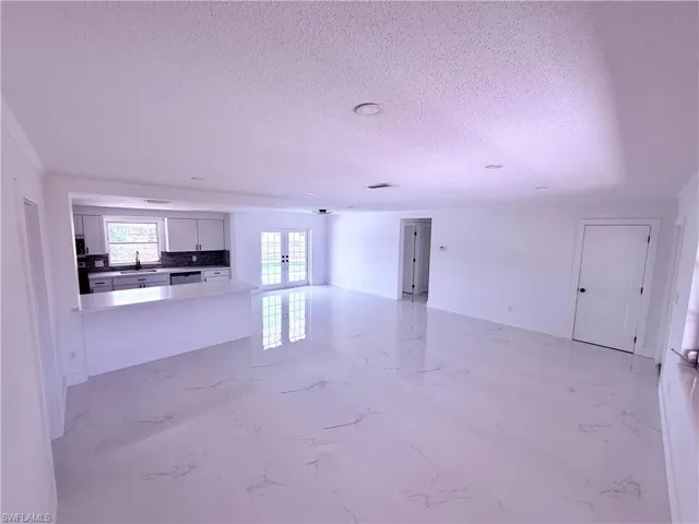 Unfurnished living room with marble finish floor, french doors, a textured ceiling, and a sink