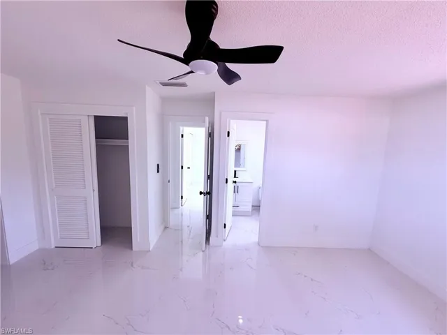 Unfurnished bedroom with a textured ceiling, baseboards, visible vents, marble finish floor, and a closet