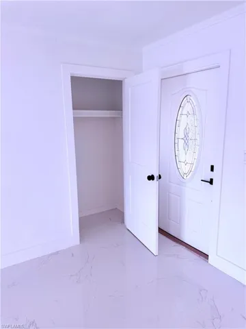 Entryway featuring marble finish floor and crown molding