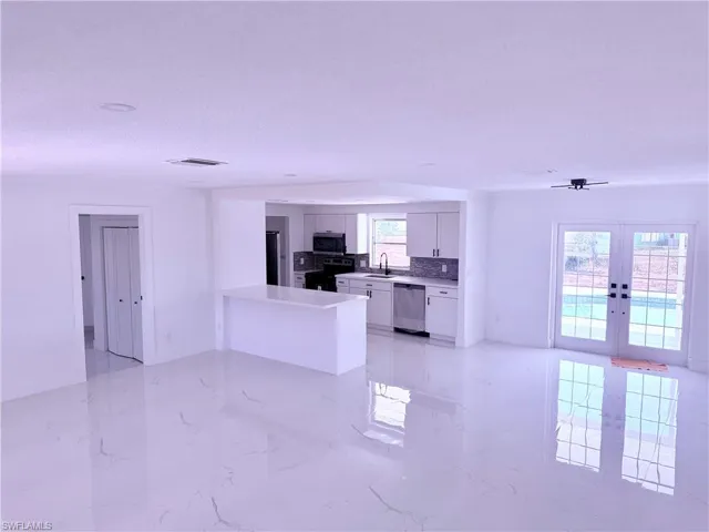Unfurnished living room featuring french doors, a sink, a textured ceiling, visible vents, and marble finish floor