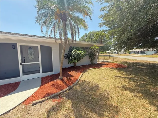 Property entrance with a yard and stucco siding