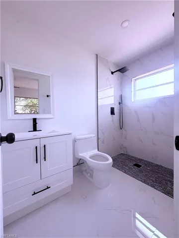 Full bathroom with marble finish floor, vanity, a marble finish shower, and toilet
