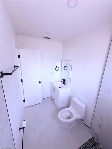 Bathroom with visible vents, marble finish floor, vanity, and toilet