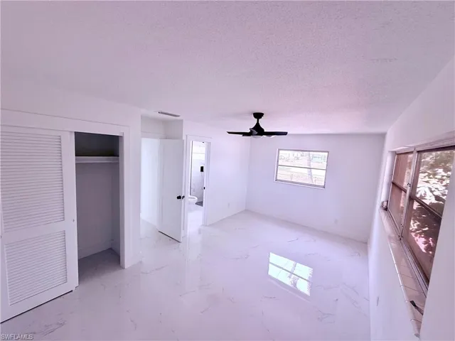 Unfurnished bedroom with a ceiling fan, a textured ceiling, a closet, marble finish floor, and visible vents