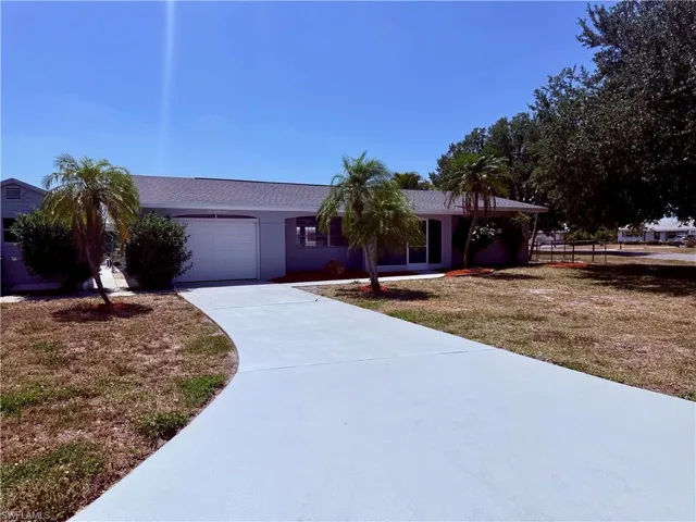 Ranch-style house with an attached garage, driveway, fence, and a front yard