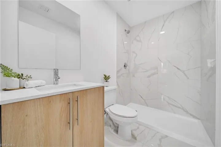 Bathroom featuring vanity, toilet, and tiled shower