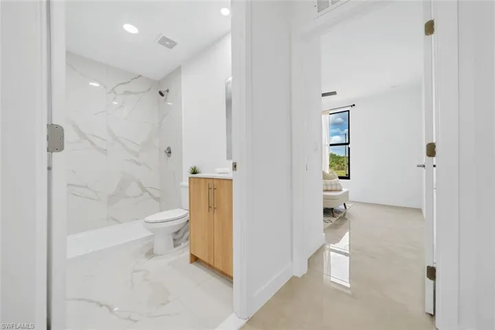Bathroom with vanity, a tile shower, and toilet
