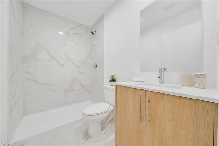 Bathroom with vanity, a tile shower, and toilet