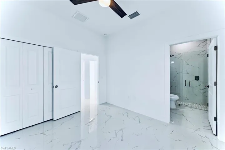 Unfurnished bedroom featuring ceiling fan, a closet, and ensuite bathroom