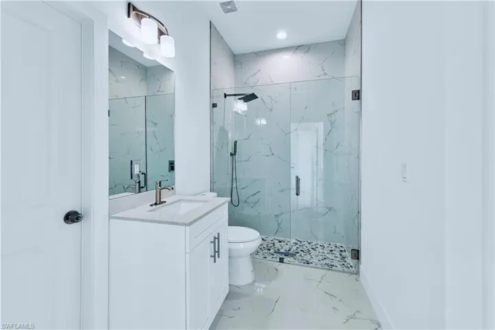 Bathroom featuring vanity, toilet, and an enclosed shower