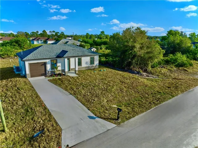 Single story home with a garage and a front lawn