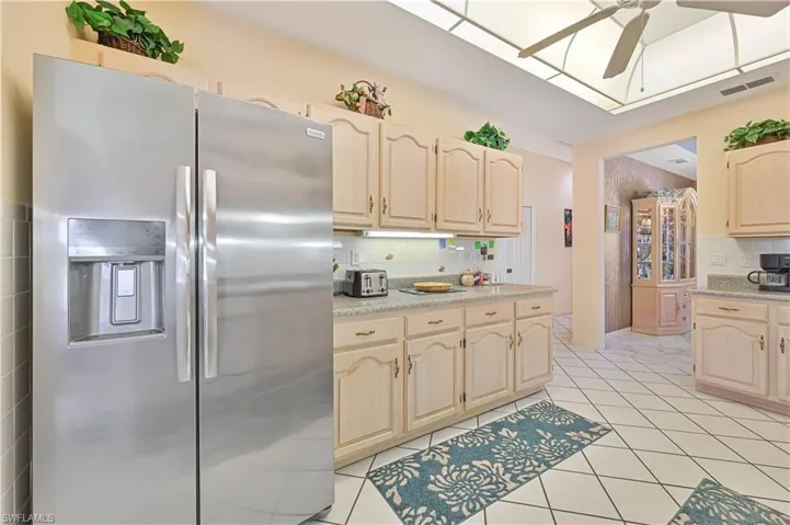 Kitchen with backsplash, stainless steel refrigerator with ice dispenser, a ceiling fan, and light countertops