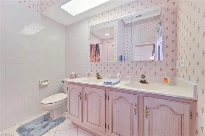 Bathroom with tile patterned flooring, double vanity, toilet, and a sink