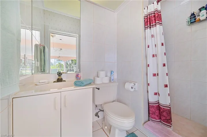 Bathroom with vanity, tile walls, toilet, tile patterned flooring, and tiled shower