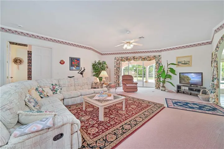 Living room featuring ornamental molding, visible vents, carpet flooring, and ceiling fan