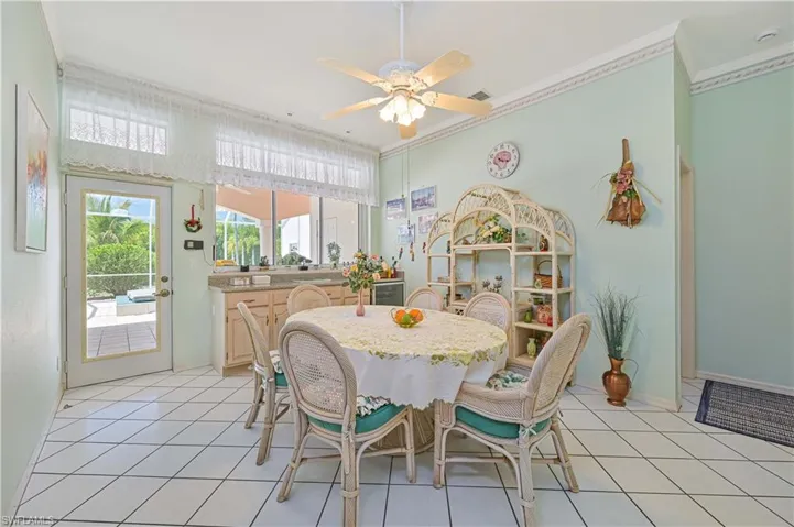 Dining area with light tile patterned floors, baseboards, ceiling fan, and crown molding