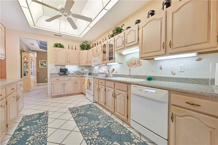 Kitchen featuring light brown cabinets, ceiling fan, and white appliances