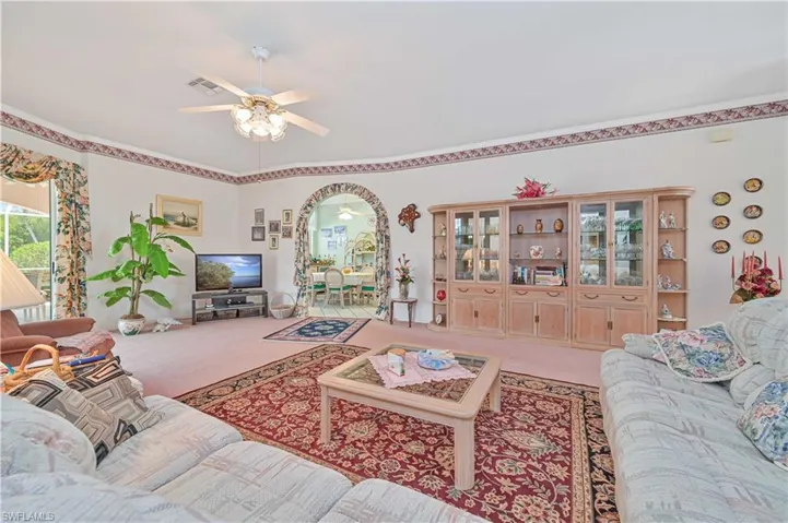 Living room featuring ornamental molding, carpet floors, a ceiling fan, and visible vents