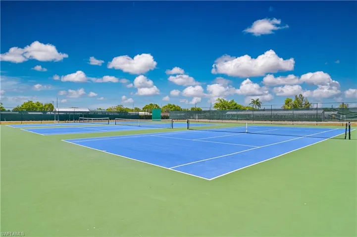 View of tennis court with community basketball court and fence
