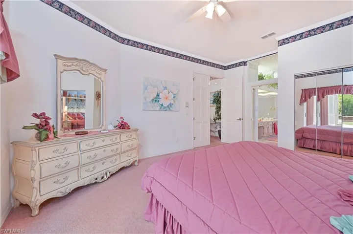 Carpeted bedroom with ensuite bath, a ceiling fan, and visible vents