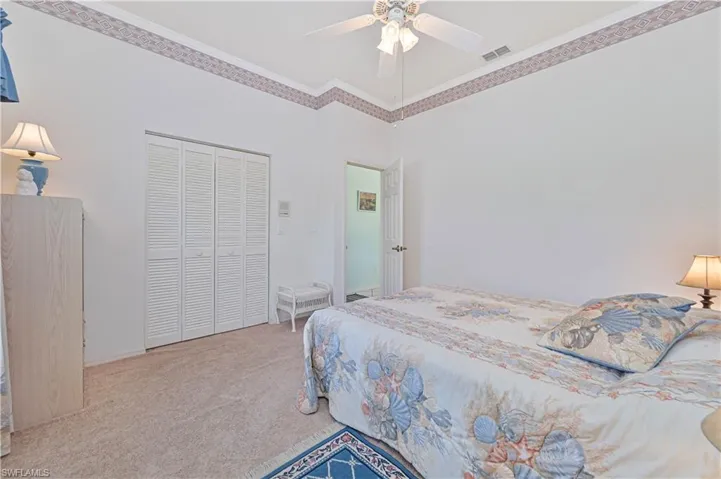 Carpeted bedroom with baseboards, visible vents, a ceiling fan, a closet, and crown molding