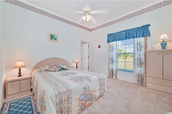 Bedroom featuring a ceiling fan, baseboards, carpet floors, and crown molding