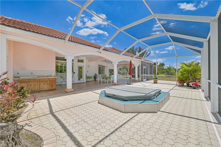 View of patio with a covered hot tub, a lanai, and area for grilling