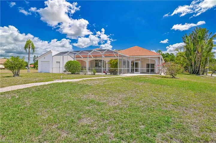 View of front of property featuring a tile roof, a lanai, a front lawn, and stucco siding