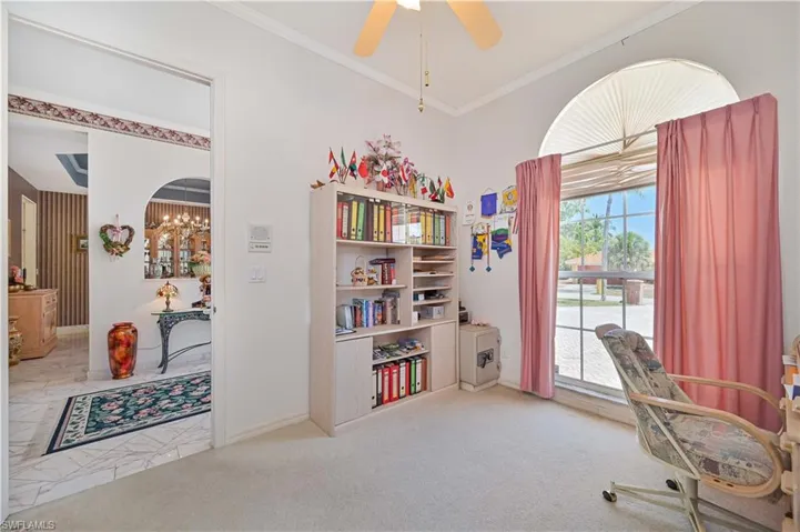 Office area featuring baseboards, crown molding, and ceiling fan with notable chandelier