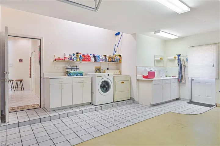 Laundry room with cabinet space, washing machine and clothes dryer, and light tile patterned floors