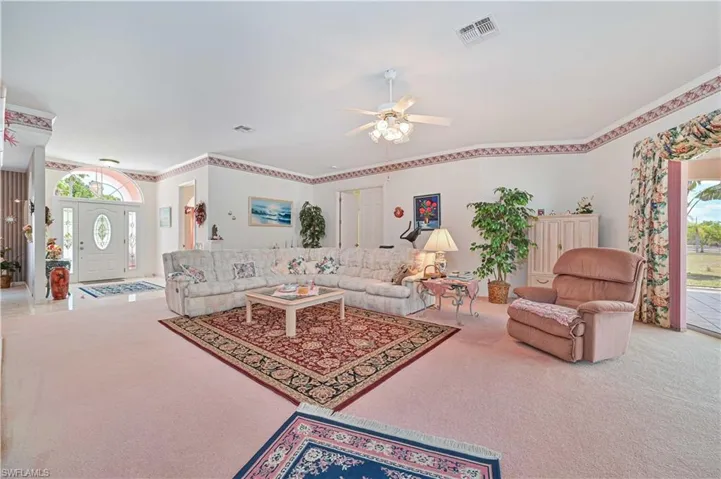 Living area with carpet, visible vents, and ceiling fan