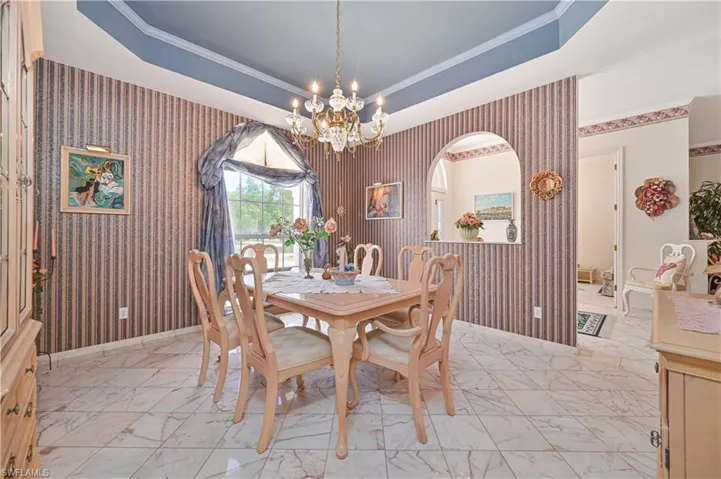 Dining space featuring crown molding, wallpapered walls, marble finish floor, and a notable chandelier